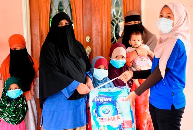NGO Persatuan Belia Dinamik Barat Seremban representative Aisha Hakimah Zaidon (right) presents a donation of daily food items to Aminah Abdullah (second from left) on 4 June, 2020. - Bernama