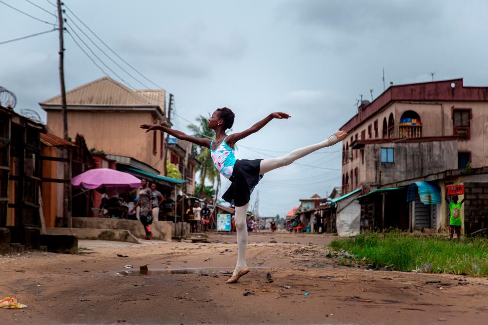 A student of the Leap of Dance Academy, Precious Duru, performs a dance routine in Okelola street in Ajangbadi, Lagos, on July 3, 2020. / AFP / Benson Ibeabuchi