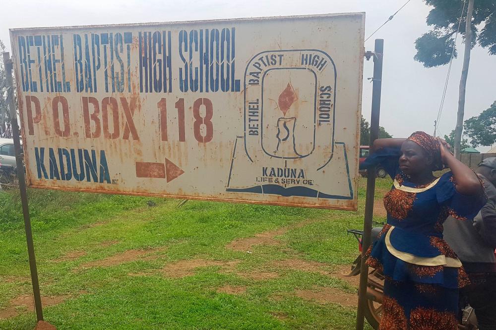 Parents stand beside signpost of Bethel Baptist School where 140 boarding students were kidnapped by bandits in Kaduna, northwestern Nigeria, on July 5, 2021. – AFP