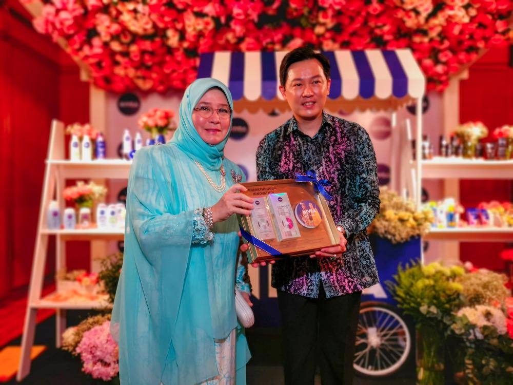 Tunku Azizah receives a hamper of Nivea products from Ng.