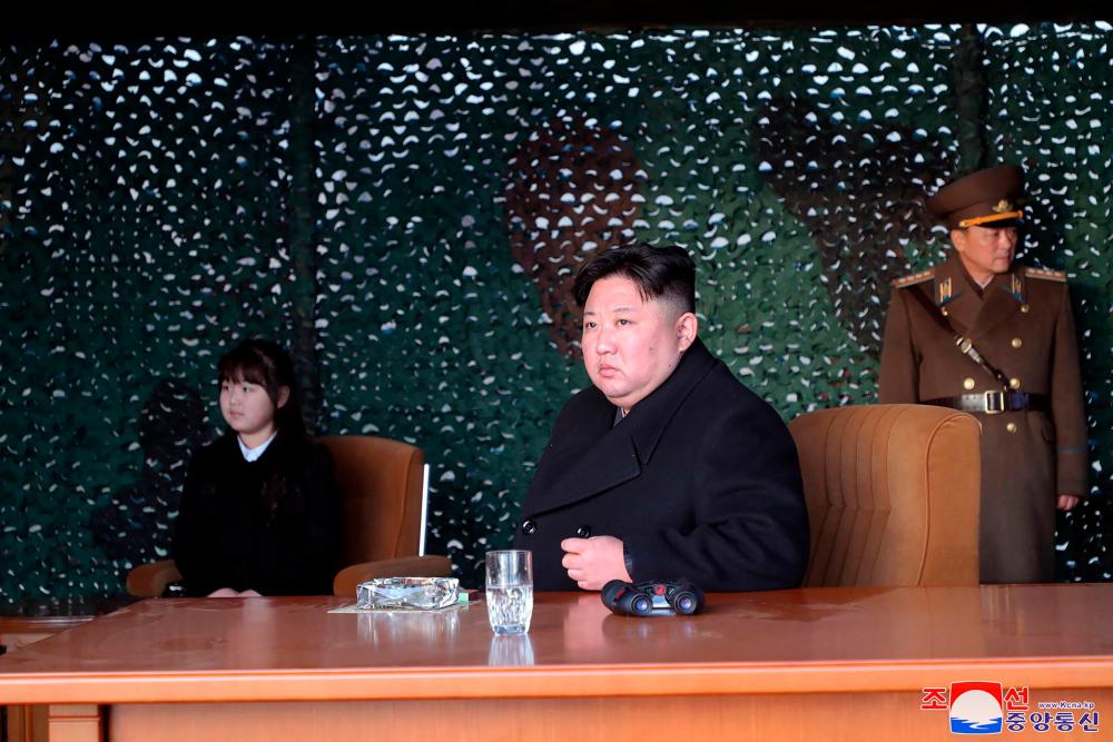 This picture taken on March 9, 2023 and released by North Korea’s official Korean Central News Agency (KCNA) on March 10 shows North Korea’s leader Kim Jong Un (C) and his daughter (L) observing the Mars Artillery Unit, responsible for important operational missions of the Korean People’s Army Western Front, as it conducts fire attack training, at an undisclosed location/AFPPix