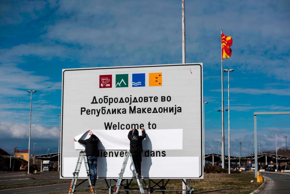 Workers tape over the old country name on a sign at the border crossing Bogorodica at the Macedonia-Greece border near Gevgelija on Feb 13, 2019. — AFP
