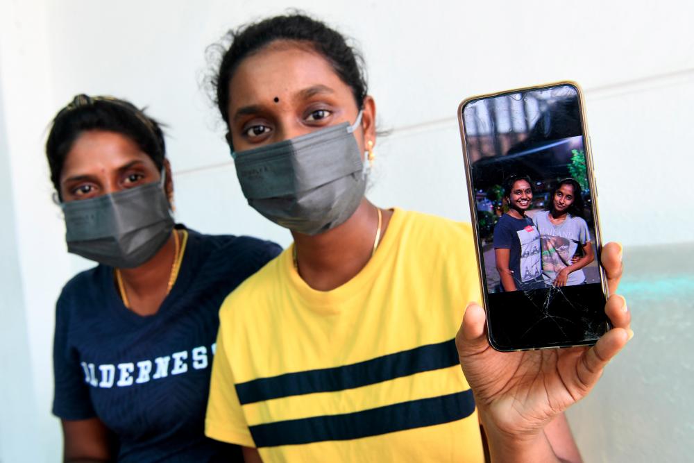 PORT DICKSON, 24 April -- R Turgadevi, 22, (kanan) ahli keluarga terdekat kepada tiga beradik mati lemas ketika mandi manda di Pantai Cahaya semalam, menunjukkan gambar terakhir bersama salah seorang mangsa, R Sathiyadevi, 19, sewaktu menunggu proses bedah siasat selesai dijalankan di Unit Forensik Hospital Port Dickson hari ini. fotoBERNAMA