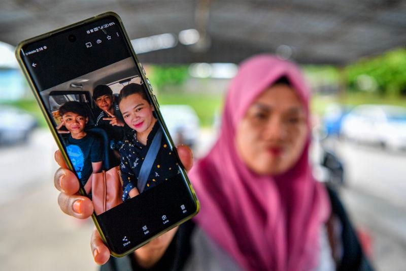 Haslinda Jupri ibu kepada arwah Mohammad Aidil Ramdan Mohd Hisham dan Mohammad Asraf Adha menunjukkan gambar kenangan bersama anaknya ketika ditemui di perkarangan luar Hospital Tuanku Jaafar, hari ini. - fotoBERNAMA