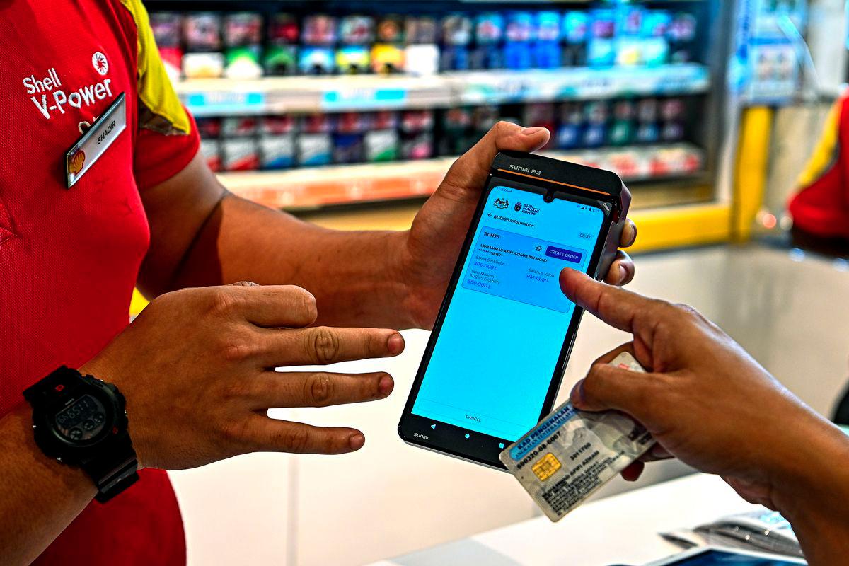 Pegawai Tentera Lt Kol Muhammad Afifi Azham Mohd (kanan) menggunakan MyTentera di kaunter pembayaran untuk pengisian petrol RON95 pada harga RM1.99 seliter berbanding RM2.05 seliter di stesen Shell Jalan Sunggala, menerusi inisiatif BUDI MADANI RON95 (BUDI95) yang bermula hari ini. - fotoBERNAMA