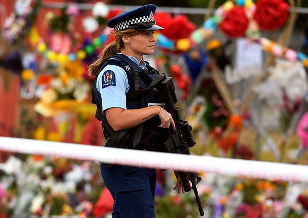 A policewoman patrols past a memorial wall outside the Linwood Mosque in Christchurch — AFP