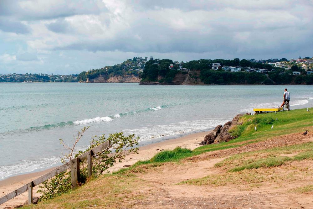 A man looks out onto a beach following a tsunami warning in Orewa, north of Auckland, on March 5, 2021, as tens of thousands of coastal residents in New Zealand, New Caledonia and Vanuatu fled for higher ground as a cluster of powerful earthquakes sparked a Pacific-wide tsunami alert. - AFP