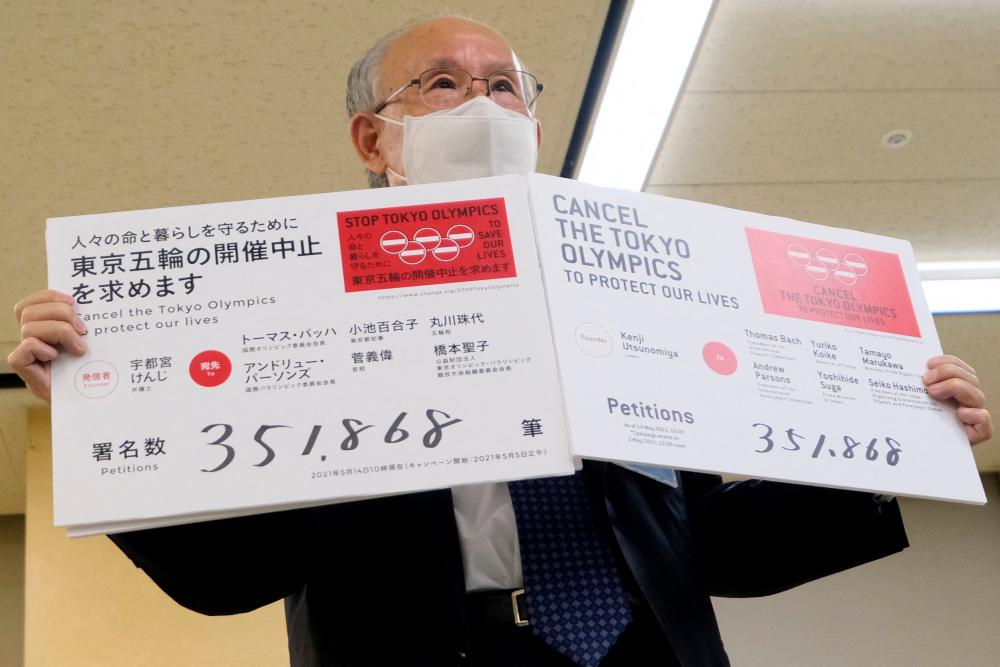This picture taken on May 14, 2021 shows Kenji Utsunomiya, a Japanese lawyer and former Tokyo gubernatorial candidate, displaying numbers of the petitions calling for the cancellation of the Tokyo Olympics during his press conference at the Tokyo Metropolitan Government in Tokyo. – AFP