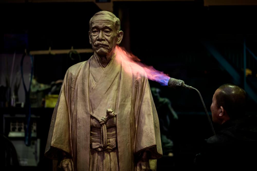 In this picture taken on February 17, 2020, a man welds an under-construction 7th edition of a cast bronze statue of Jigoro Kano, the founder of judo, created by Japanese sculptor Fumio Asakura, at the Okamiya Art Foundry in Kawaguchi, Saitama prefecture. / AFP / Yasuyoshi CHIBA /