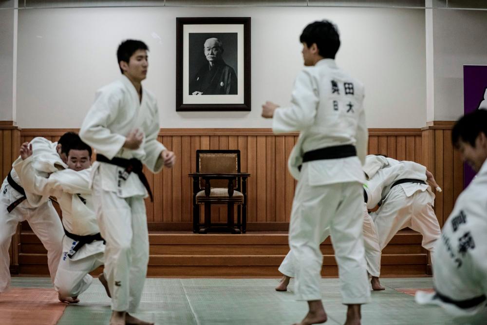 $!In this picture taken on February 19, 2020, judokas wrestle in front of a portrait of Jigoro Kano, the founder of judo, hung above his chair and desk after a weekly free-style practice session at the Kodokan, judo’s headquarters, in Tokyo. / AFP / Yasuyoshi CHIBA / ACKAGE