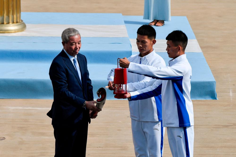 Vice President of the Chinese Olympic Committee Yu Zaiqing (L) holds the flame, ready to travel to Beijing during the Olympic flame handover ceremony at Panathinean stadium in Athens, on October 19, 2021. AFPpix