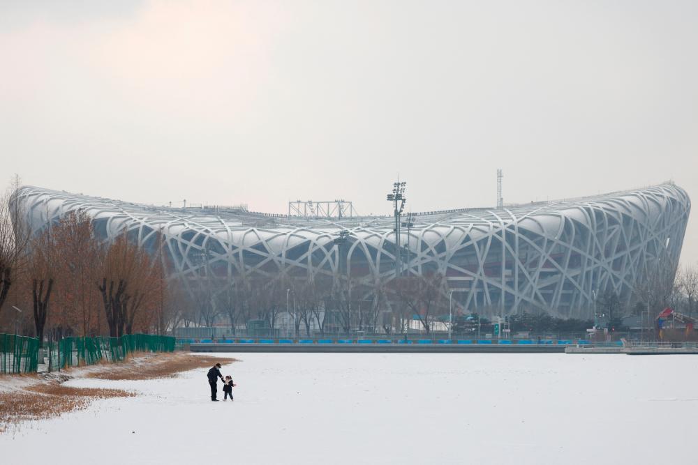 People stand on a snow-covered area outside the National Stadium, also known as the Bird's Nest, where the opening and closing ceremonies of Beijing 2022 Winter Olympics will be held, in Beijing, China January 20, 2022. REUTERSpix