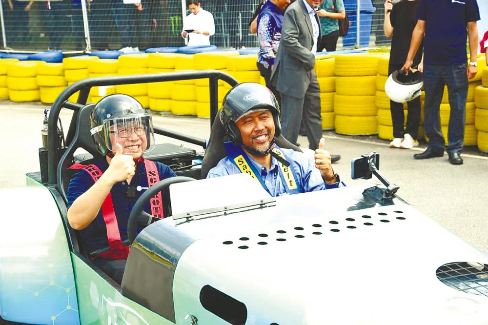 Chang (left) and Rezal test driving a hydrogen-powered car after the launch of HyPEReactor.