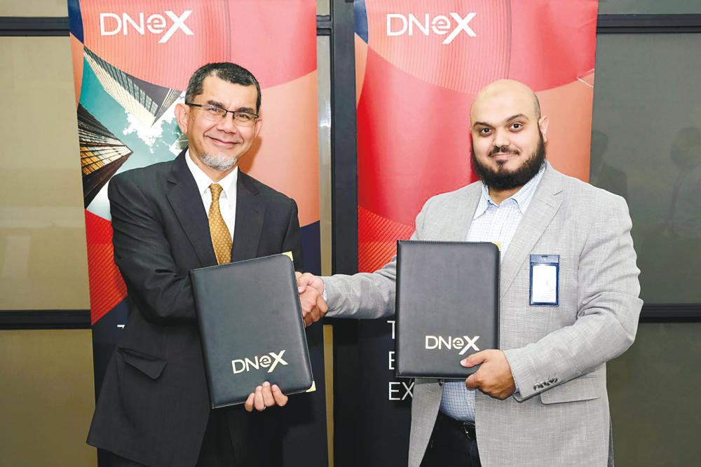 Syed Zainal (left) and CEO AnalytX of Ajlan &amp; Bros Holding Group Dr Tariq Alshawi exchanging MoU documents.