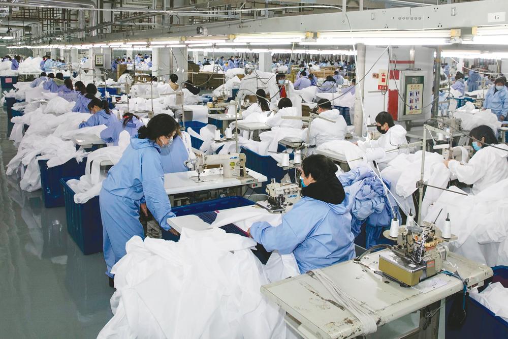 Workers producing protective clothing at a factory in Wuxi, in China’s eastern Jiangsu province. The factory, which previously produced suits and sportswear, switched to production of protective clothing as demand increases due to the ongoing coronavirus outbreak. – AFPPIX