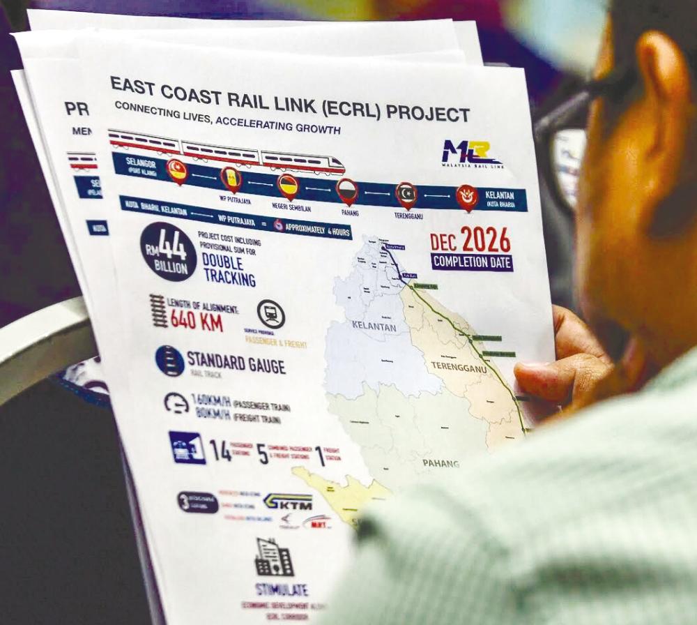 A reporter reading a fact sheet on the ECRL at a press conference in Putrajaya today. – Ashraf Shamsul/THESUN