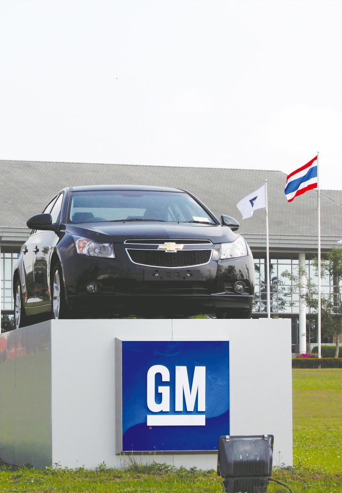 The Thai national flag and a car are displayed in front of the General Motors (GM) plant in Rayong province. GM will sell it’s Thai plant to China’s Great Wall Motor Co. – REUTERSPIX
