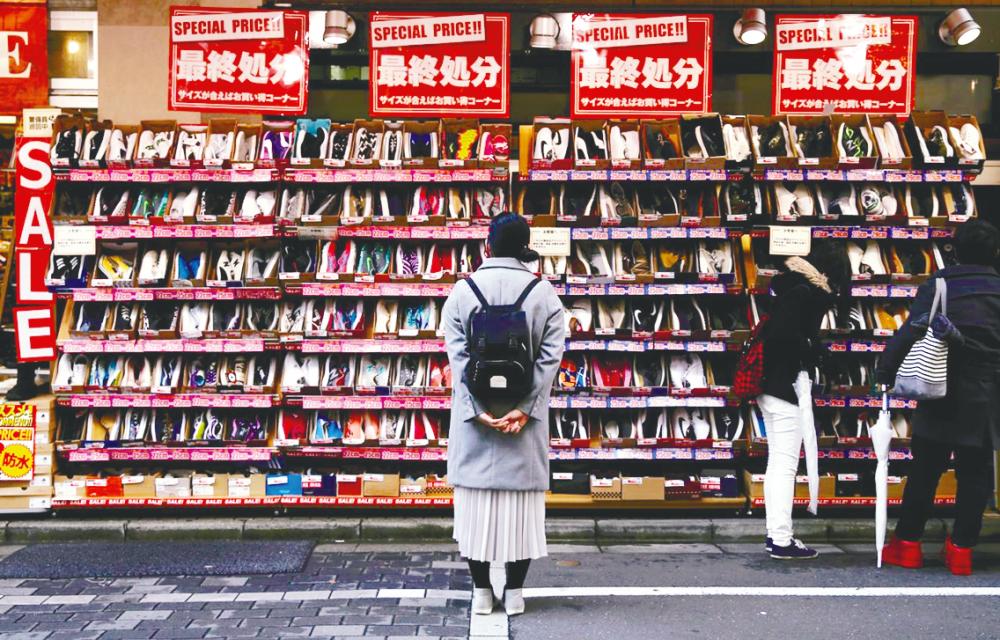 A woman looks at shoes on sale at an outlet store in Tokyo’s shopping district. A survey shows 84% of consumers still use notes and coins for small purchases. – REUTERSPIX