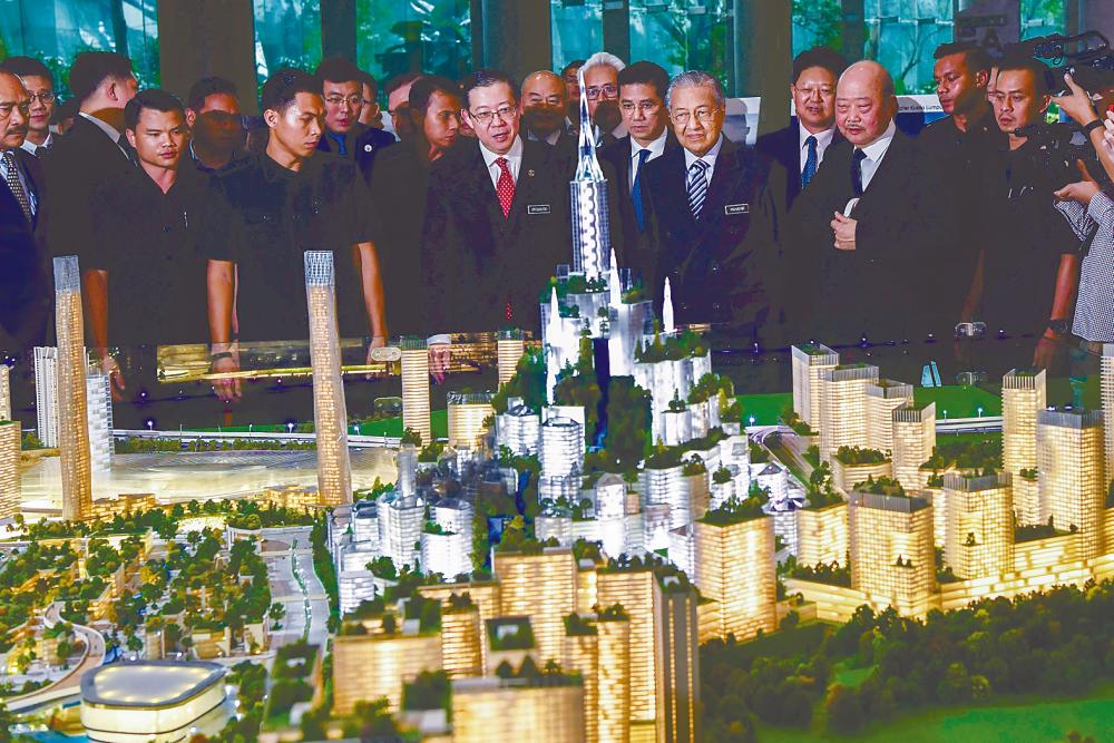 Mahathir looking at a model of the revised Bandar Malaysia project in Putrajaya today. With him are Lim, Economic Affairs Minister Datuk Seri Mohamed Azmin Ali and Iskandar Waterfront Holdings executive vice chairman Tan Sri Lim Kang Hoo. – BERNAMAPIX