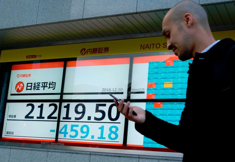 A man walks in front of a stock indicator board showing share prices of the Tokyo Stock Exchange in Tokyo today. – AFP