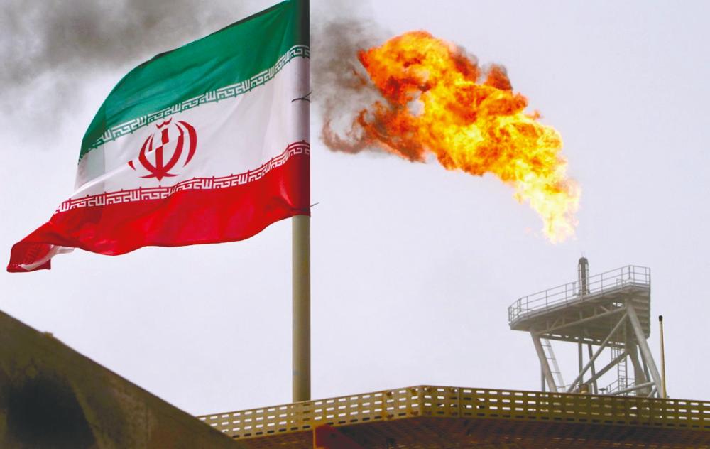 A gas flare on an oil production platform in the Soroush oil fields is seen alongside an Iranian flag in the Persian Gulf, Iran. – REUTERSPIX