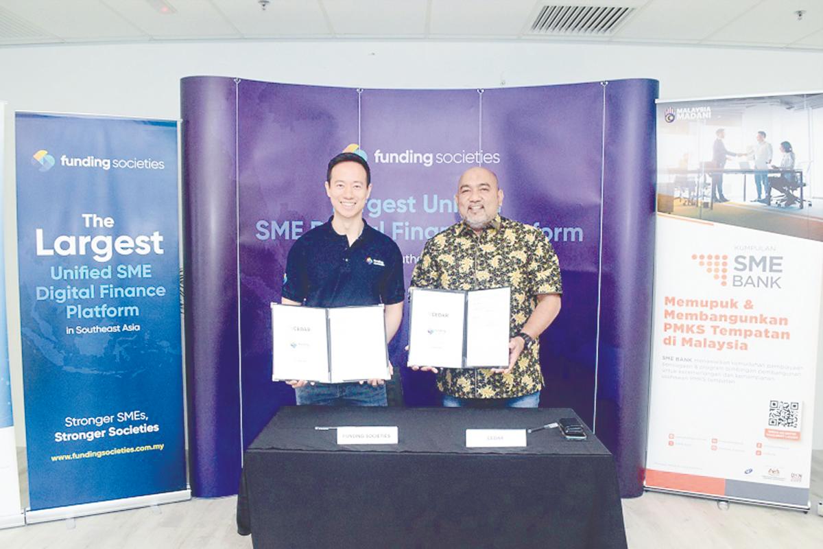 Kah (left) and Hairil Izwar displaying the signed documents.