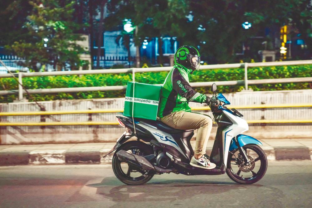 A Gojek rider delivering a Tokopedia package to a customer in Jakarta. – AFPPIX/GoTo Group