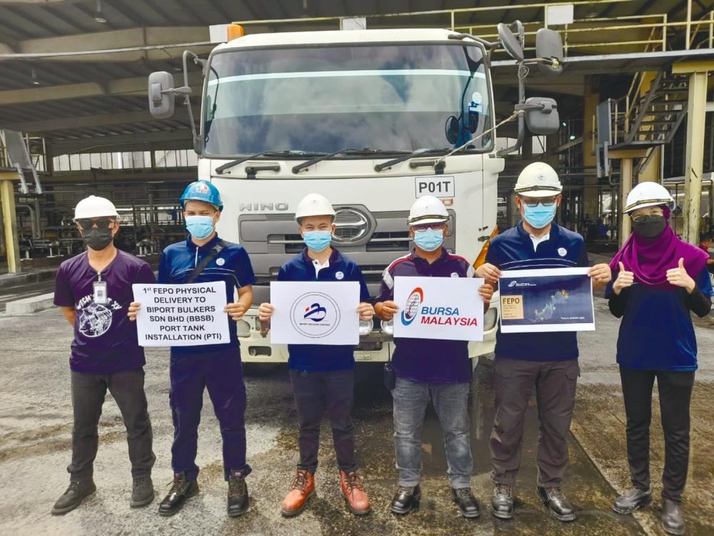 Workers at the approved Port Tank Installation with signs commemorating the completion of Bursa Malaysia Derivatives’ first Fepo physical delivery in Sarawak.