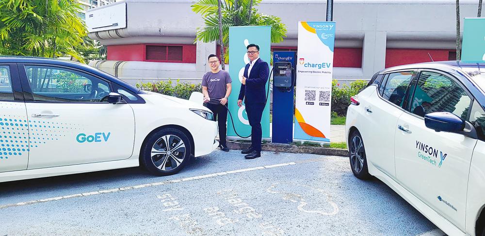 Wong (left) and Ruslin charging up GoEV’s Nissan Leaf using a chargEV charging station at the MoU signing ceremony.