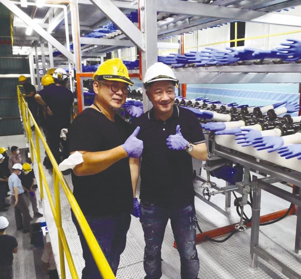 Choong (left) and AT Systemization executive director Mak Siew Wei giving the thumbs up while touring the glove manufacturing plant.
