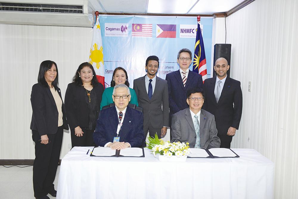 Bustos (seated left) and Chung at the MoC signing ceremony yesterday. Looking on are (from left) NHMFC’s Luisa Favila, vice-president Rosabella C. Jose, executive vice-president Livia Alicia R. Ramos, Cagamas assistant vice-president Sekaran Chandra Kumar, senior vice-president Leong See Meng, and vice-president Mandeep Singh Sandhu.