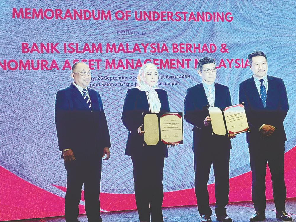 Sarah (second from left) and Nomura Asset Management Sdn Bhd director Atsuchi Ichii (second from right) displaying the signed documents.