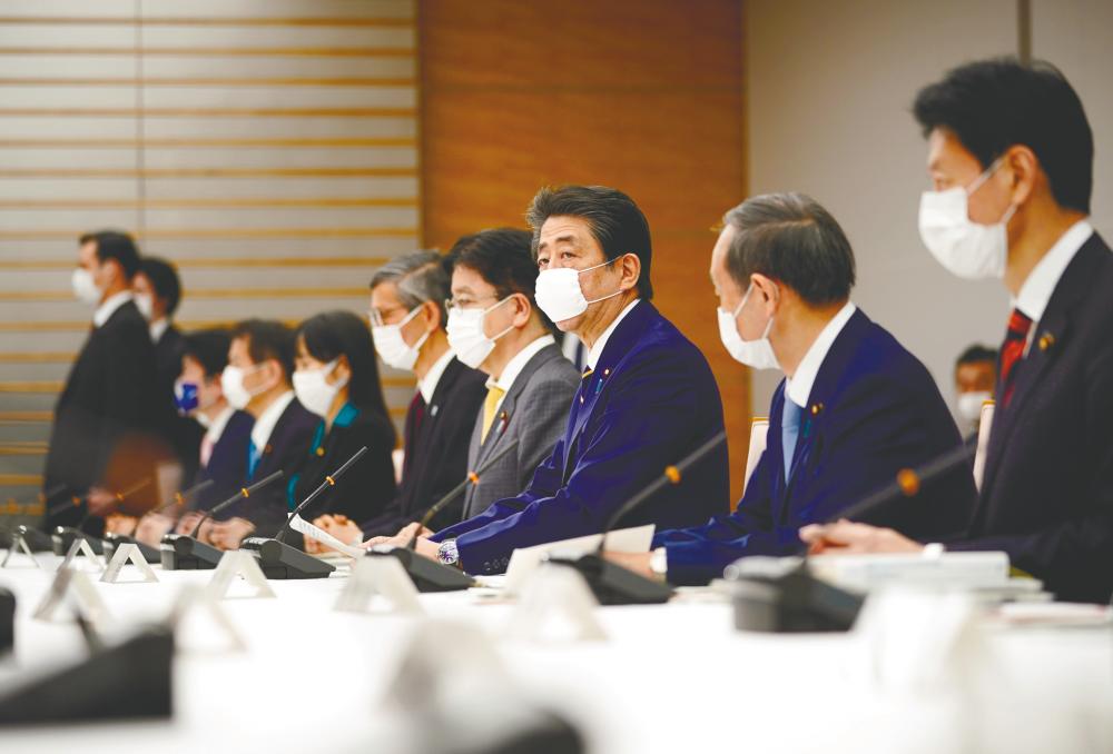Abe (third from right) declares state of emergency during a meeting of the new coronavirus task force at the prime minister's official residence in Tokyo today. – REUTERSPIX