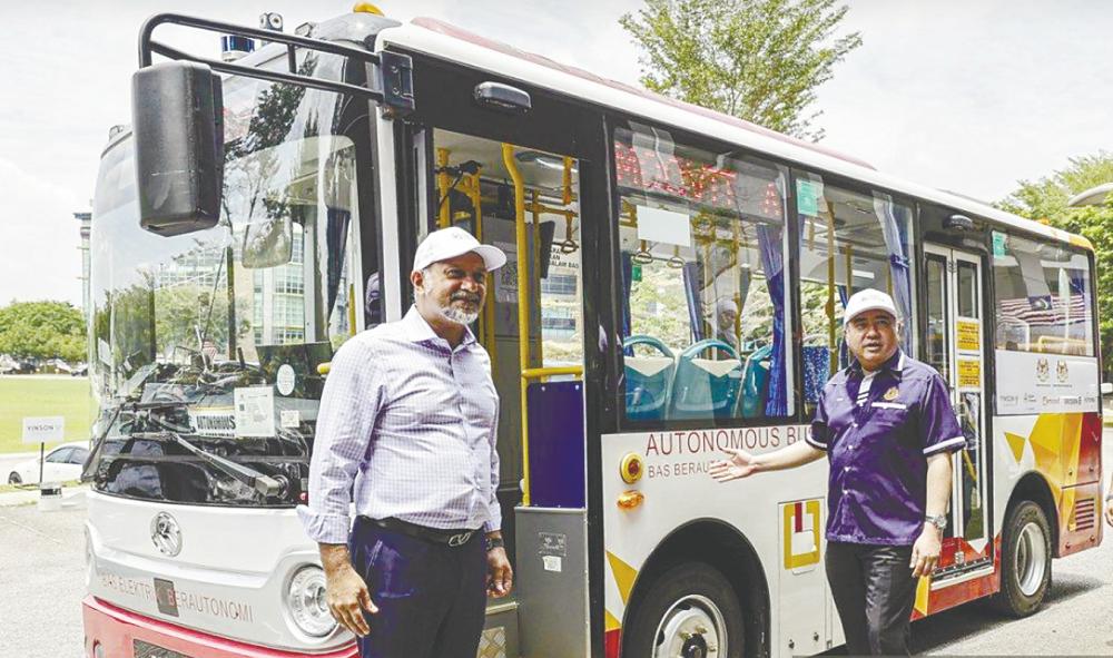 Gobind (left) and Loke with a 5G-enabled autonomous bus during a use-case demonstration at Futurise Centre. – Bernamapic