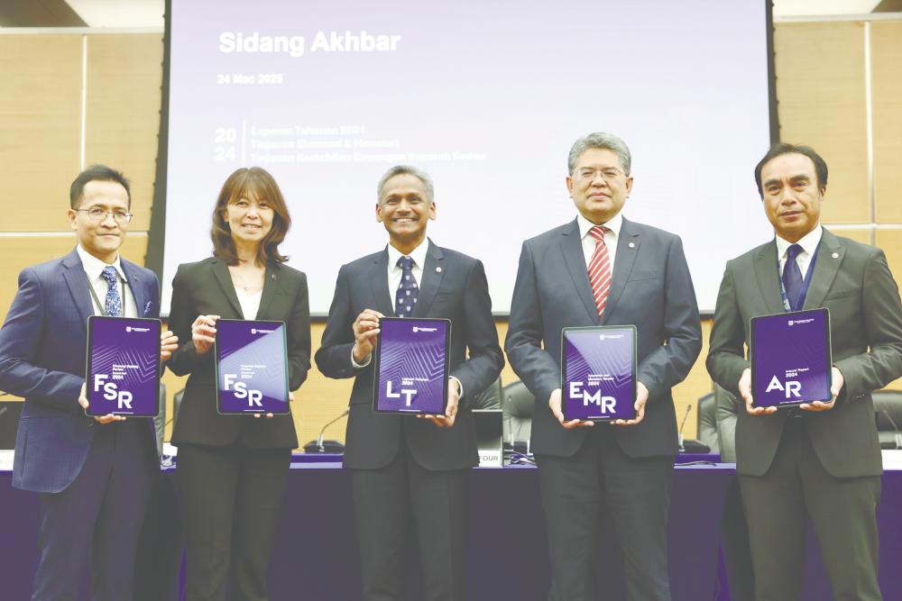 Abdul Rasheed (centre) and other Bank Negara Malaysia officials displaying the central bank’s flagship publications today. – Bernamapic