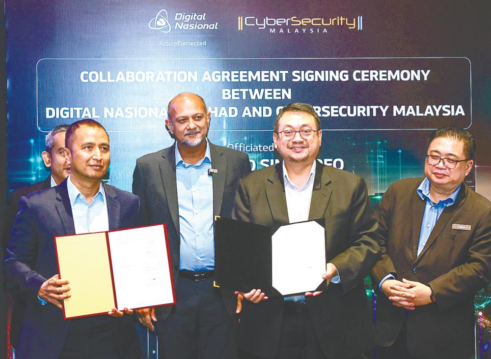 Gobind (second from left) witnessing the exchange of documents between DNB chief operating officer Nasution Mohamed (left) and CyberSecurity Malaysia CEO Datuk Dr Amirudin Abdul Wahab today. – Bernamapic