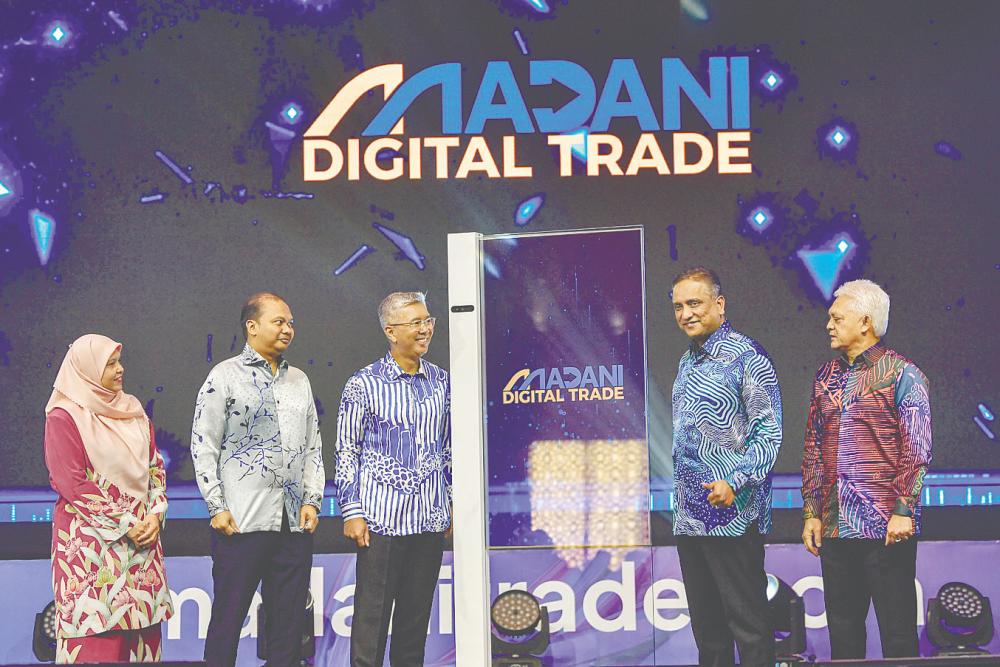 Tengku Datuk Seri Zafrul Abdul Aziz (centre) officiating at the launch of Madani Digital Trade today. With him are Matrade chairman Datuk Seri Reezal Merican Naina Merican (second, right), CEO Datuk Mohd Mustafa Abdul Aziz (right) and Nazsoft Tech CEO Dr Muhammad Nazrol Zawawi (second, left). – Bernamapic