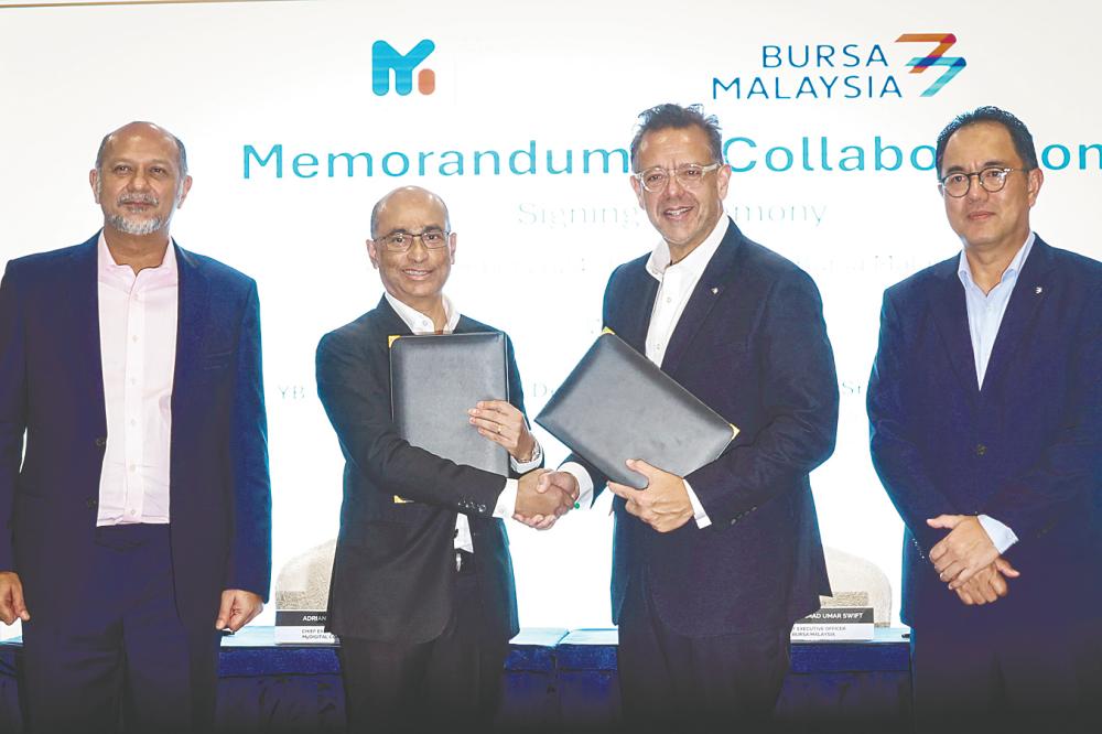 Gobind (left) and Bursa Malaysia senior independent director Tan Sri Abdul Faris Alias (right) witnessing the exchange of documents between MyDigital Corp CEO Adrian Marcellus (second from left) and Muhammad Umar. – Bernamapic