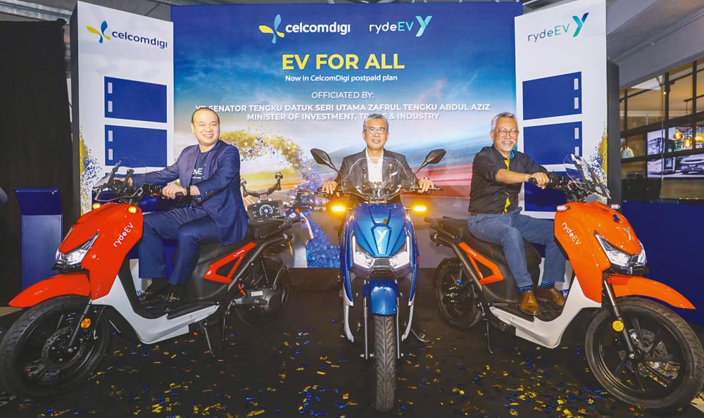 From left: Lim, Tengku Zafrul and Idham trying out the rydeEV e-bike at the launch of the CelcomDigi-Yinson partnership.