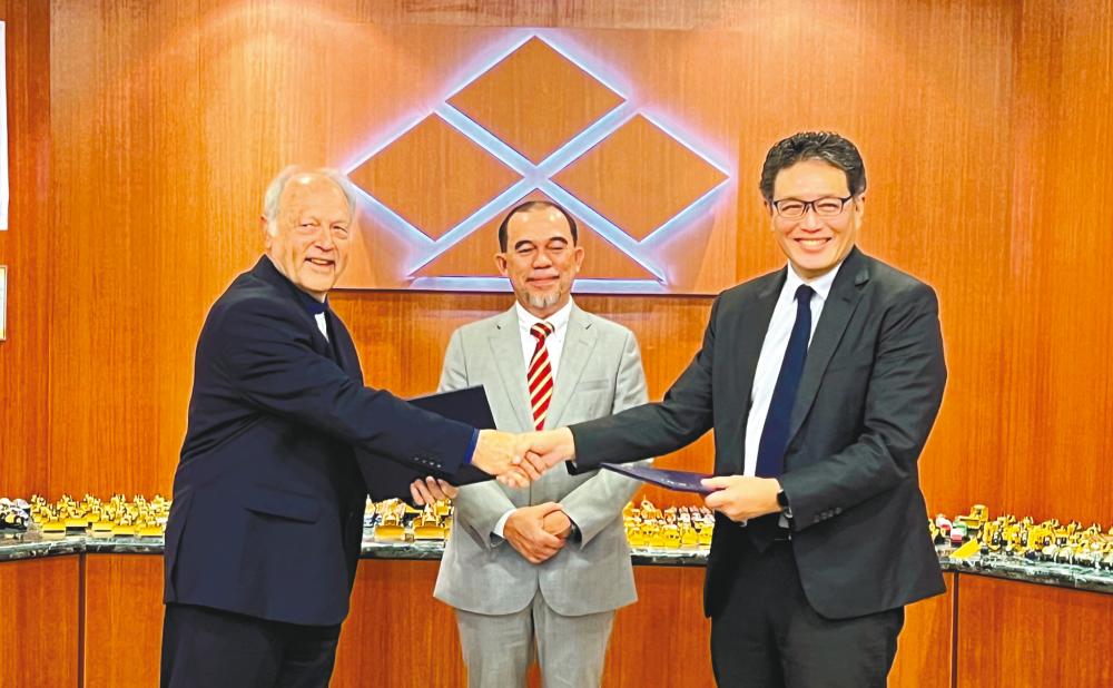 Thornton (left) exchanging MoUs with Chia, witnessed by Sarawak Timber Industry Development Corporation adviser Datu Hashim Bojet.