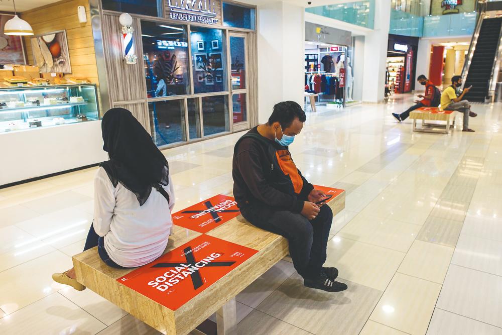 People sit on benches with sections marked off for social distancing at a mall in Surabaya on Monday. Panellists at the CARI roundtable say Asean governments need to help SME address cash flow problems directly by providing loan support to keep them afloat until demand goes back to normal. – AFPPIX