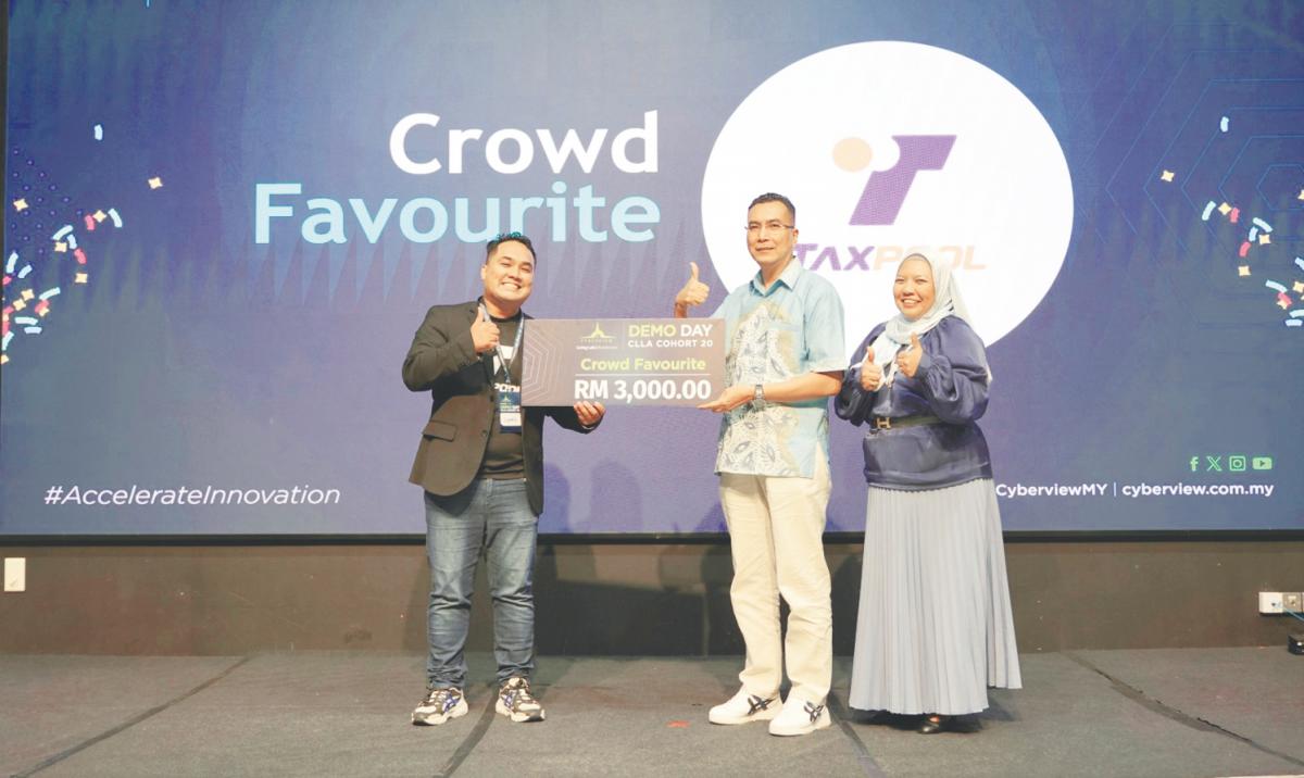Syamil (left) receiving the Crowd Favourite Award from Cyberview Sdn Bhd CEO Kamarul Ariffin Abdul Samad. On the right is Cyberview technology hub development division head Shafinaz Salim.