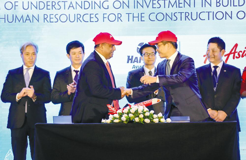 Fernandes (front, left) shakes hands with Tran after the memorandum signing witnessed by Vietnamese Deputy Prime Minister Vu Duc Dam (centre right) and Vietnamese Deputy Minister of Culture, Sports and Tourism Le Quang Tung (centre left).