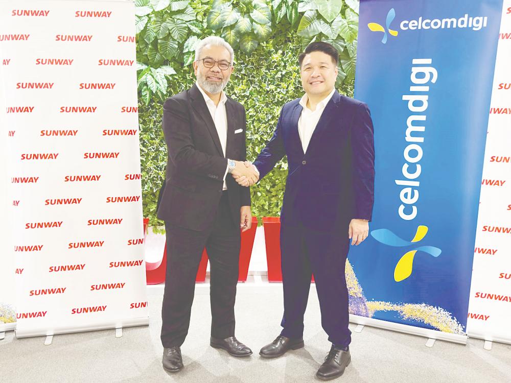 Afizulazha (left) and Khoo marking the collaboration between Sunway Group and CelcomDigi.