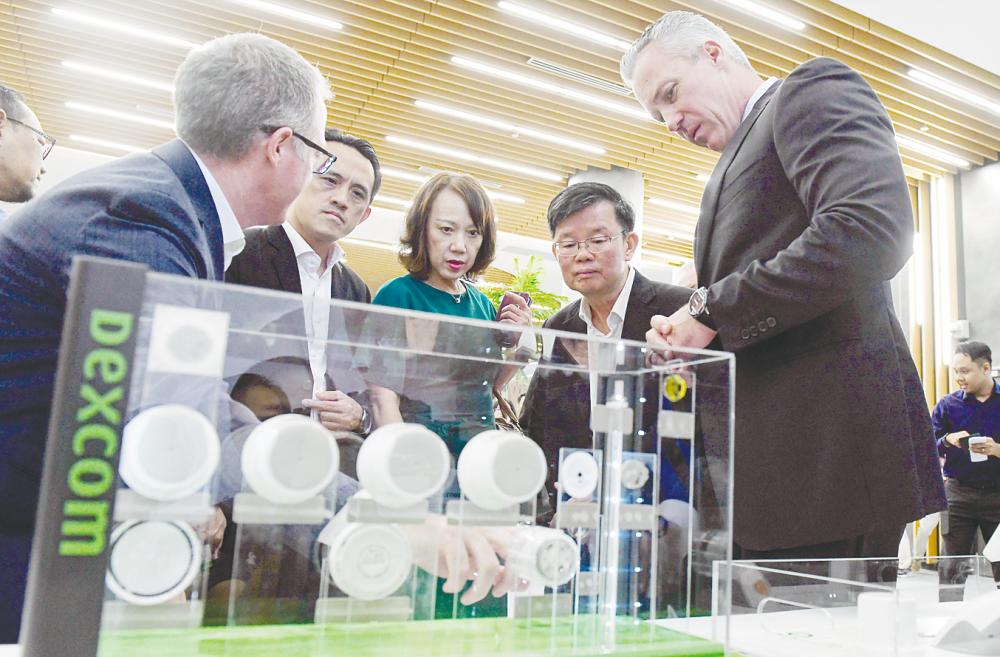 Dexcom Malaysia vice-president Columba McGarvey (left) briefing Chow (second from right) on the products of Dexcom after the official opening of the company’s manufacturing facility at Batu Kawan Industrial Park today. – Bernamapic