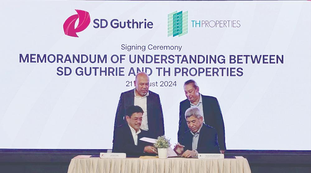 Mohamad Helmy (standing, left) and Wan Hashimi witnessing the signing of a memorandum of understanding between SD Guthrie chief land management officer Ab Razak Khamis (left) and TH Properties board member Zarulakmar Abd Aziz.