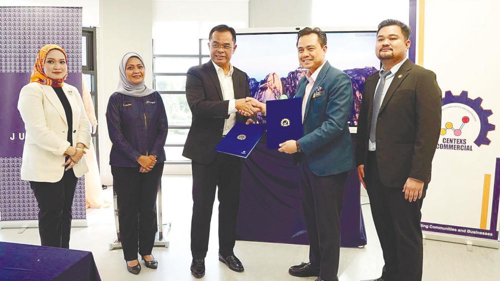 Azman (third from left) and Mohamad Shahren exchanging the signed documents.