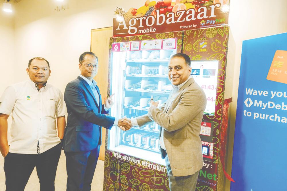 From left: Fama market institution division director Sharizan Mansor, Shahrizan and PayNet group CEO Farhan Ahmad at the launch of the grocery vending machine.