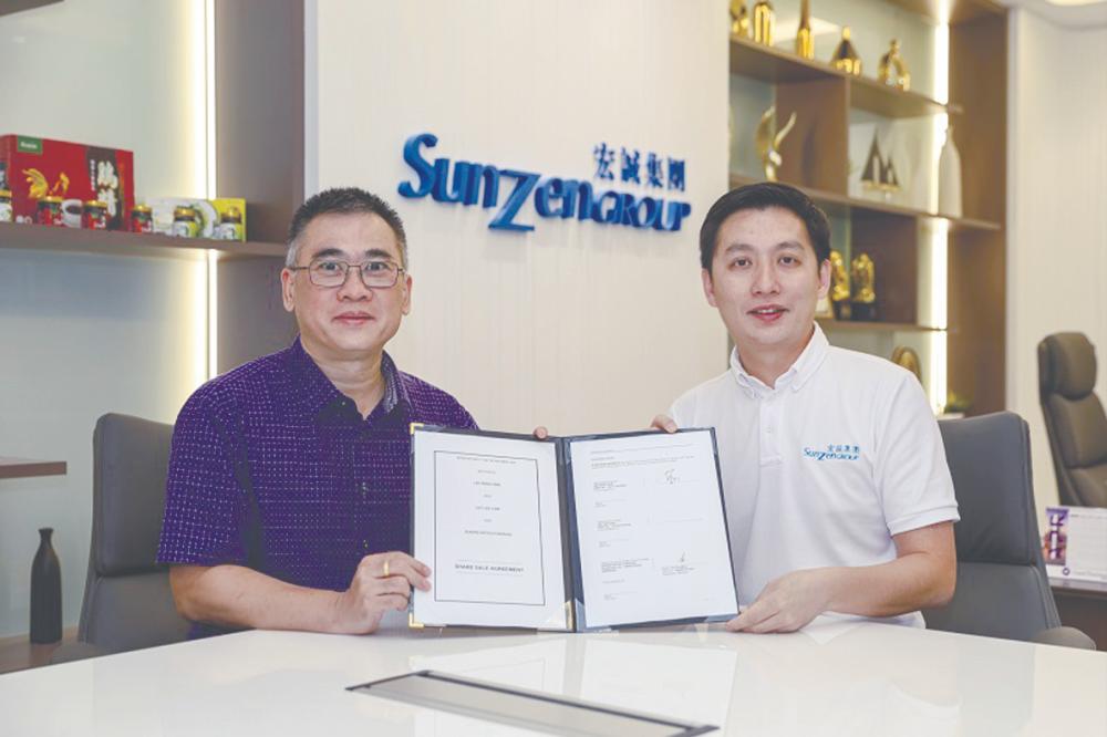 Lee (left) and Teo displaying the share sale agreement.