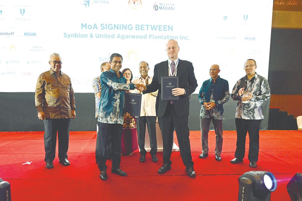 Zambry (far left) looks on as Umpsa Holdings CEO Syed Alwi Mohamed Sultan (left) and Iba Botanicals CEO Benjamin Mead, exchange documents.